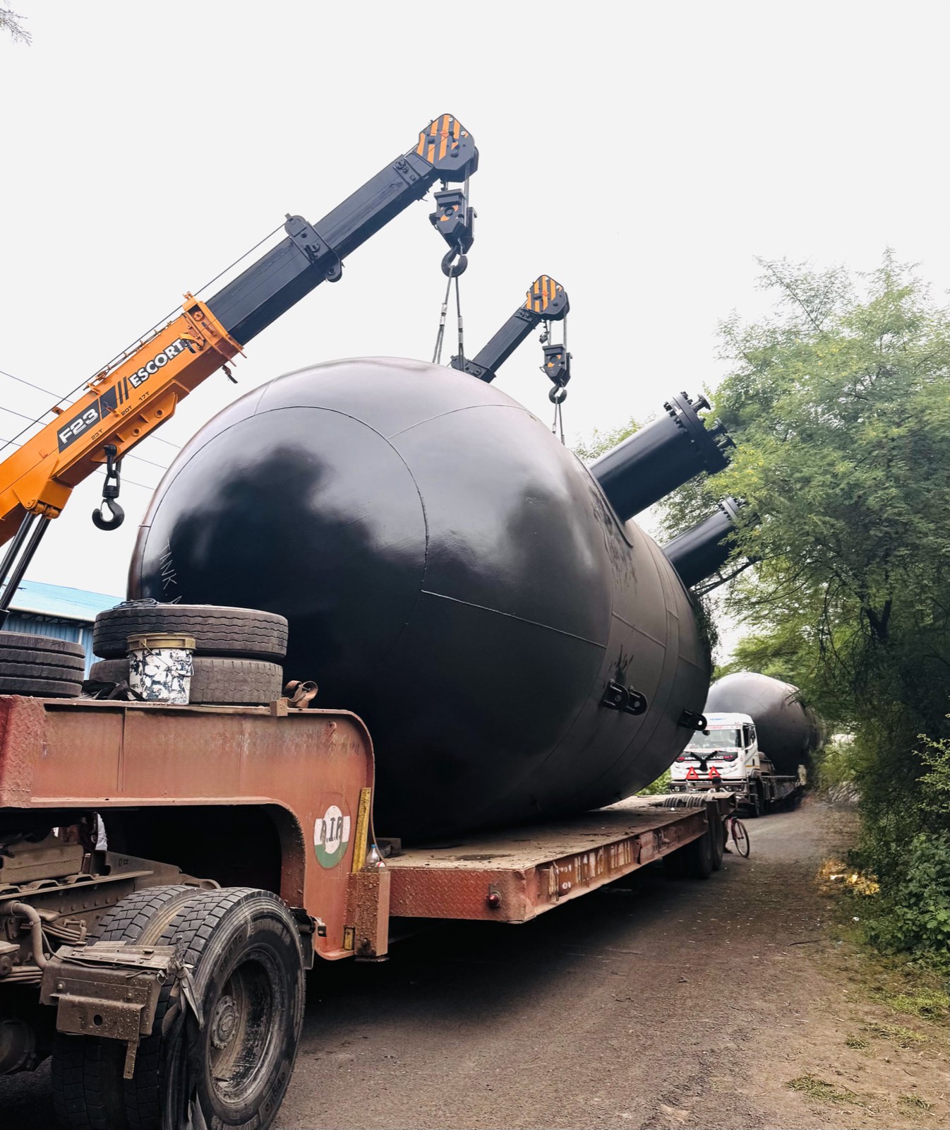 Black reactor head being positioned by two cranes onto a trailer