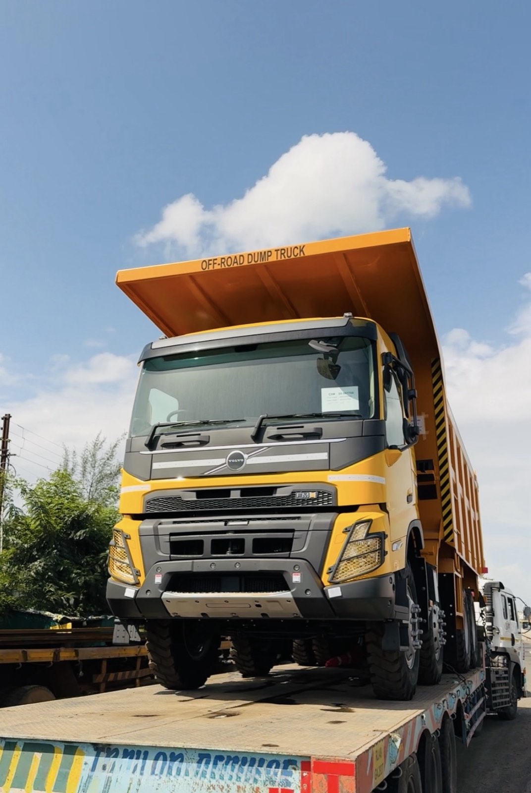 Yellow Volvo off-road dump truck carried on a flatbed